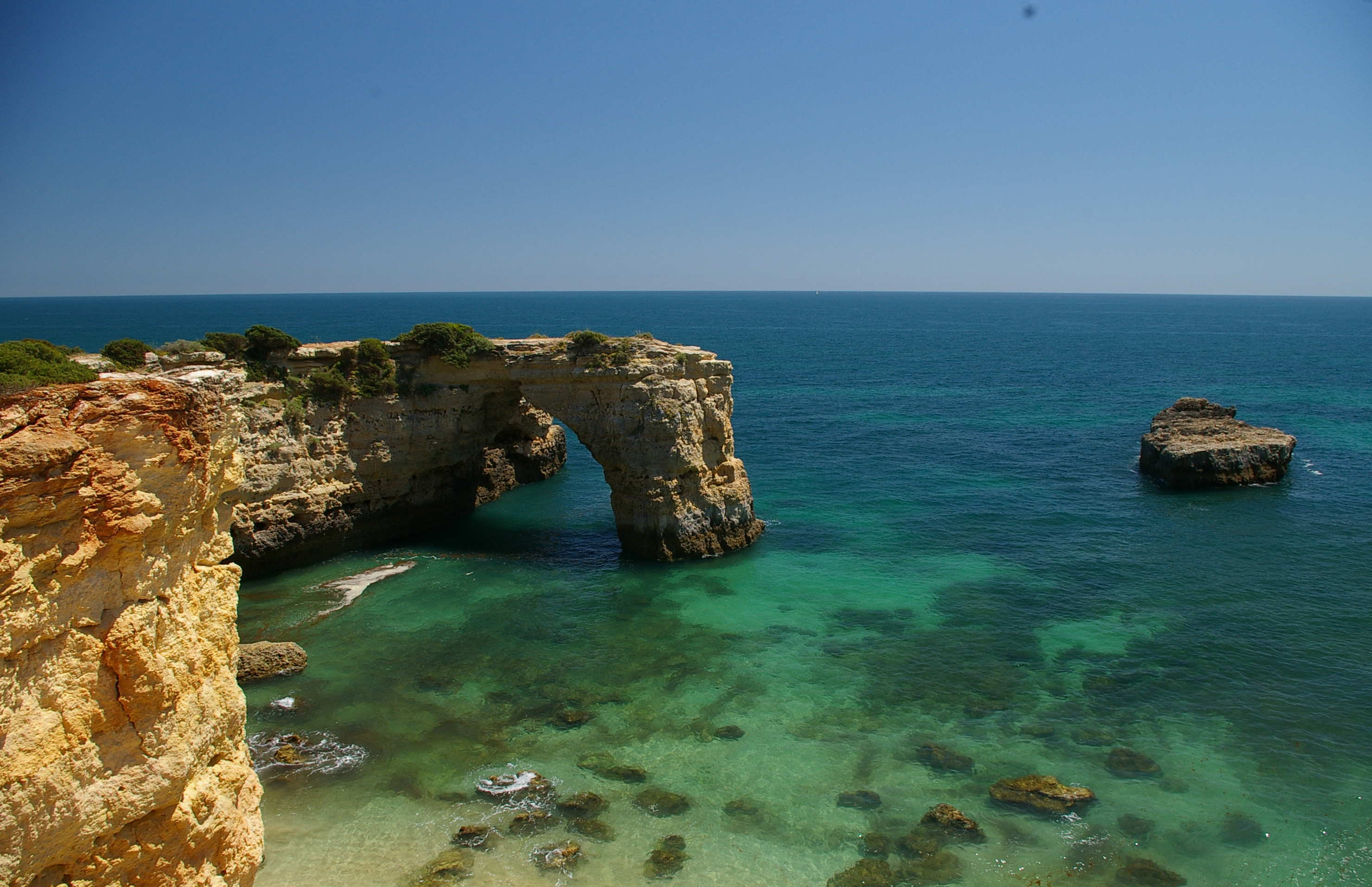 View of the atlantic ocean looking north over the stone arch at Albandeira beach Algarve Portugal